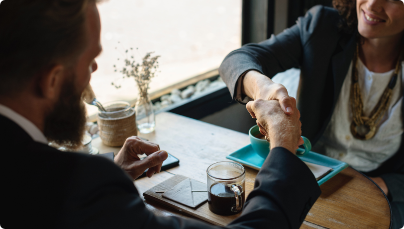 A business women shakes business man's hand after closing a deal